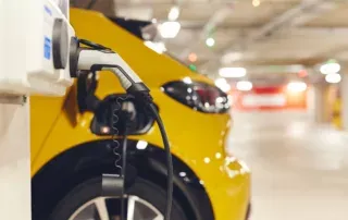une voiture électrique connectée à la borne de recharge dans un parking